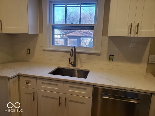 kitchen with dishwasher, light stone countertops, white cabinetry, sink, and decorative backsplash