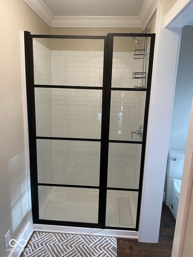 interior space with toilet, crown molding, and a shower stall