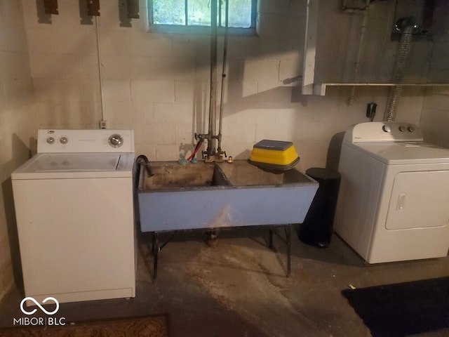 laundry room featuring concrete block wall, washing machine and clothes dryer, a sink, and laundry area