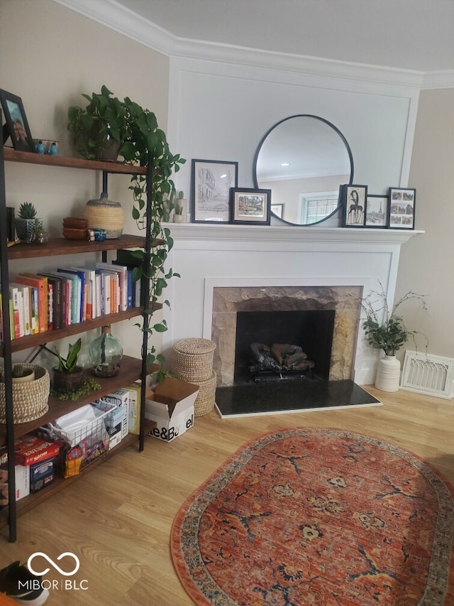 living area with a premium fireplace, light wood-type flooring, and ornamental molding