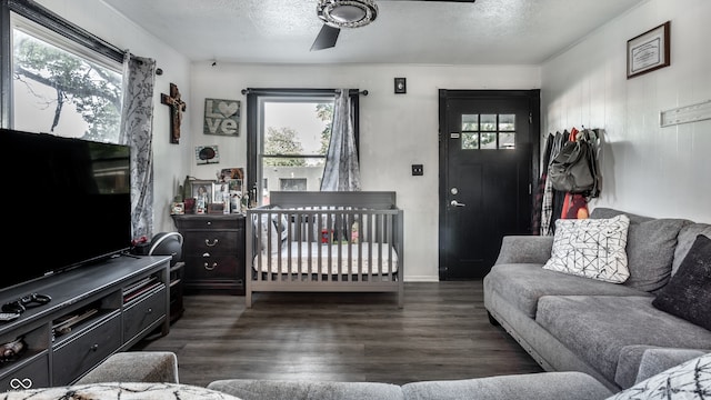 living room featuring ceiling fan, dark wood-type flooring, and a textured ceiling