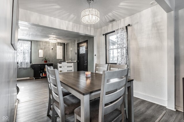 dining space featuring dark hardwood / wood-style flooring and an inviting chandelier