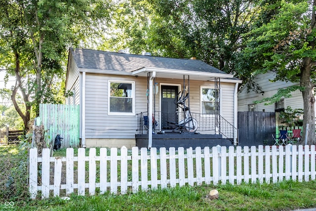 bungalow-style house featuring a shingled roof, a fenced front yard, and a porch