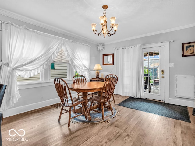 dining space with light hardwood / wood-style floors, an inviting chandelier, and ornamental molding