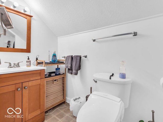 bathroom with vaulted ceiling, vanity, tile patterned flooring, a textured ceiling, and toilet