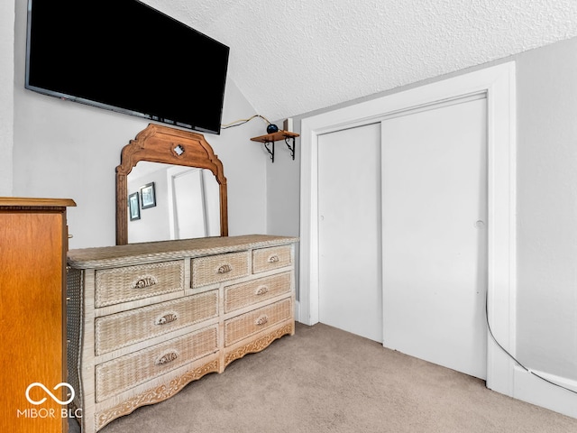 carpeted bedroom featuring a textured ceiling, a closet, and vaulted ceiling