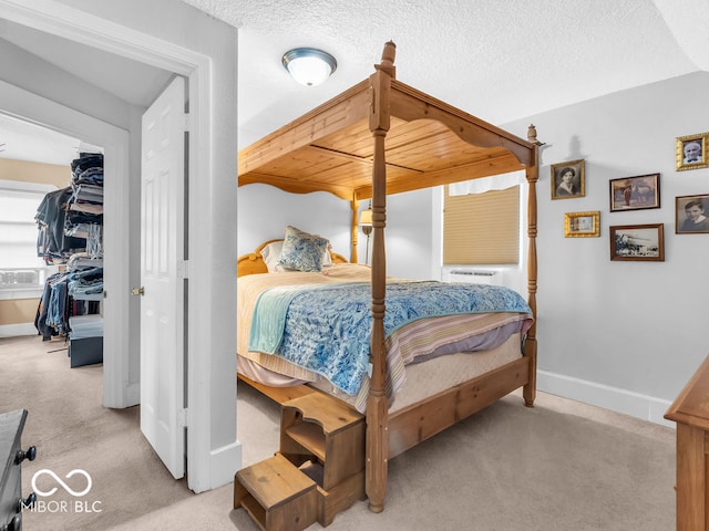 bedroom with a textured ceiling, light carpet, and cooling unit