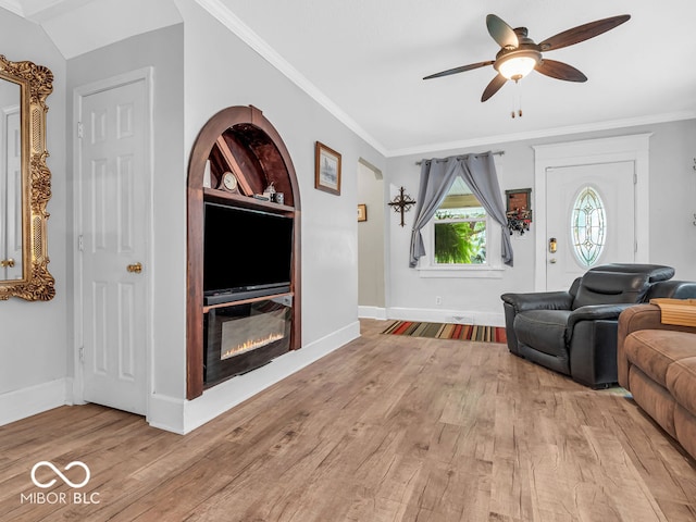 living room with light wood-type flooring, ornamental molding, ceiling fan, and built in shelves