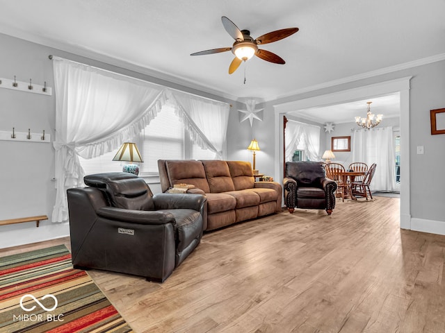 living room with plenty of natural light, light hardwood / wood-style floors, ceiling fan with notable chandelier, and crown molding