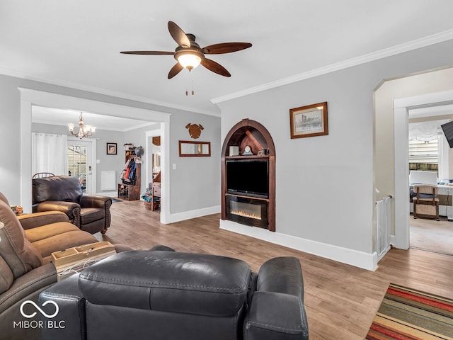 living room with light hardwood / wood-style flooring, crown molding, and ceiling fan with notable chandelier