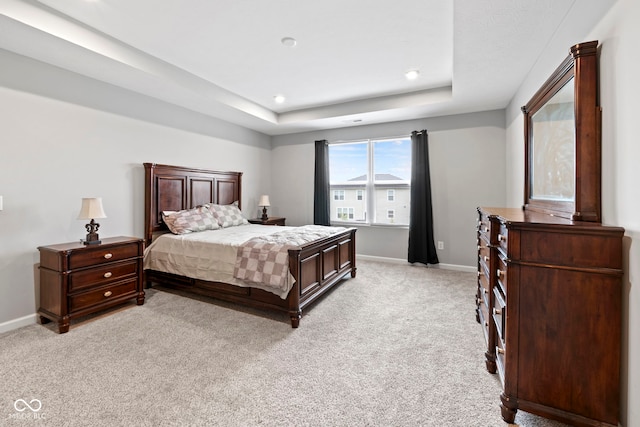 bedroom featuring a raised ceiling and light carpet