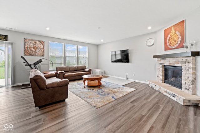 living room with plenty of natural light, hardwood / wood-style floors, and a stone fireplace