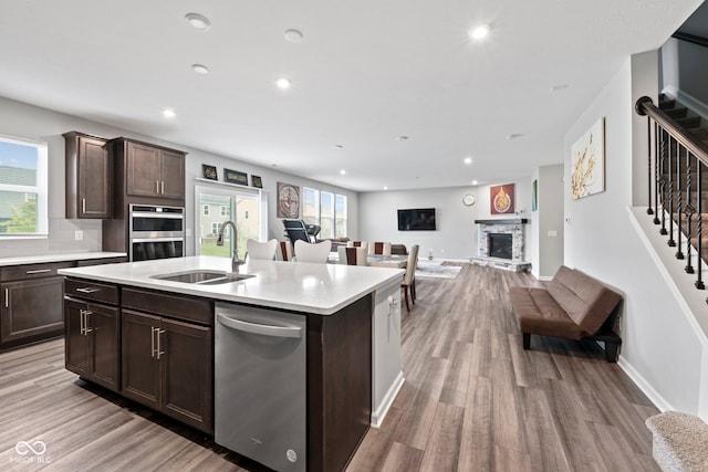 kitchen featuring sink, a healthy amount of sunlight, a center island with sink, and a fireplace