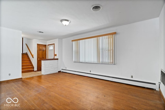 unfurnished room with hardwood / wood-style flooring and a baseboard radiator