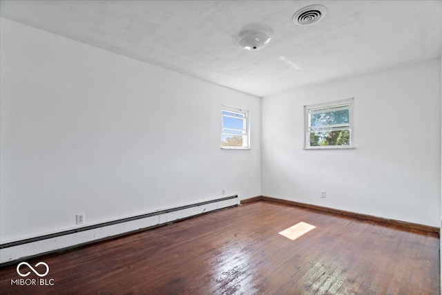 empty room featuring hardwood / wood-style floors and a baseboard heating unit