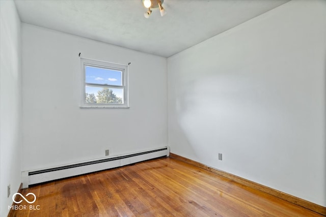 unfurnished room featuring baseboard heating and hardwood / wood-style flooring