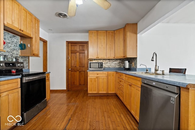 kitchen featuring light hardwood / wood-style floors, ceiling fan, tasteful backsplash, sink, and stainless steel appliances