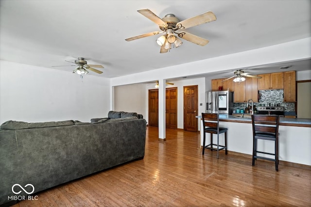 living room with dark wood-type flooring, sink, and ceiling fan