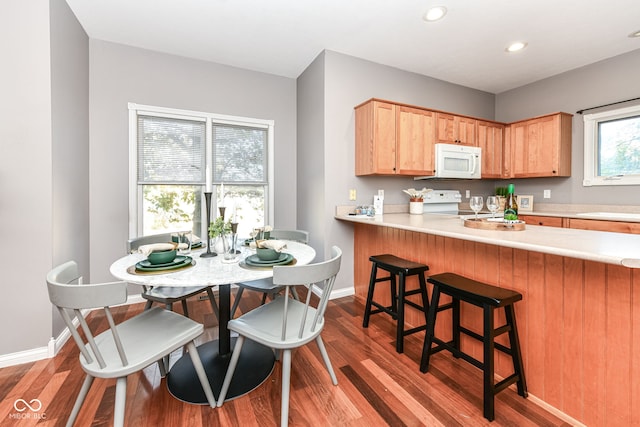 kitchen featuring light hardwood / wood-style flooring, a kitchen bar, and white appliances