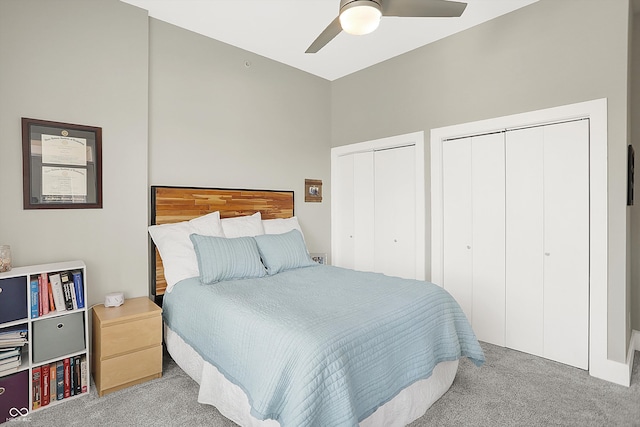 bedroom featuring ceiling fan, multiple closets, and light carpet