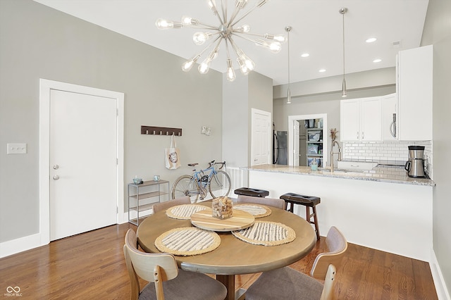 dining room with sink, dark hardwood / wood-style floors, and an inviting chandelier