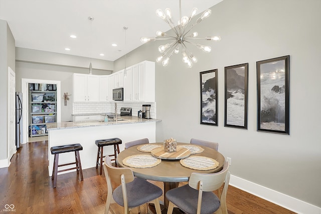 dining room featuring sink, dark wood-type flooring, and an inviting chandelier