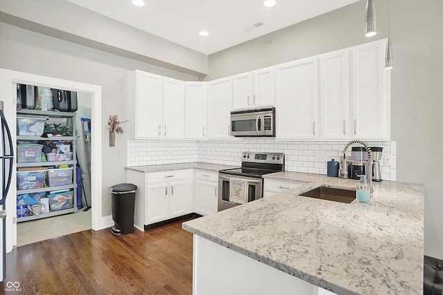 kitchen featuring dark hardwood / wood-style flooring, decorative backsplash, appliances with stainless steel finishes, white cabinetry, and light stone counters