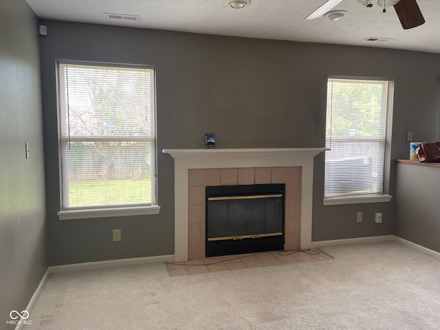 unfurnished living room featuring ceiling fan, light colored carpet, and a tiled fireplace