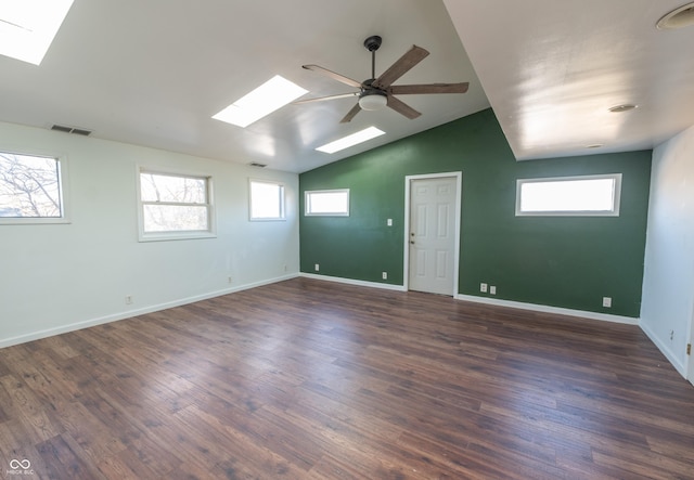 spare room featuring ceiling fan, dark wood-type flooring, and lofted ceiling with skylight