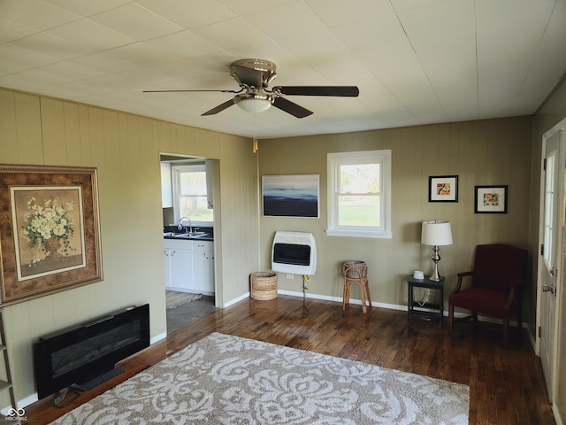 living area featuring heating unit, sink, dark hardwood / wood-style floors, and ceiling fan