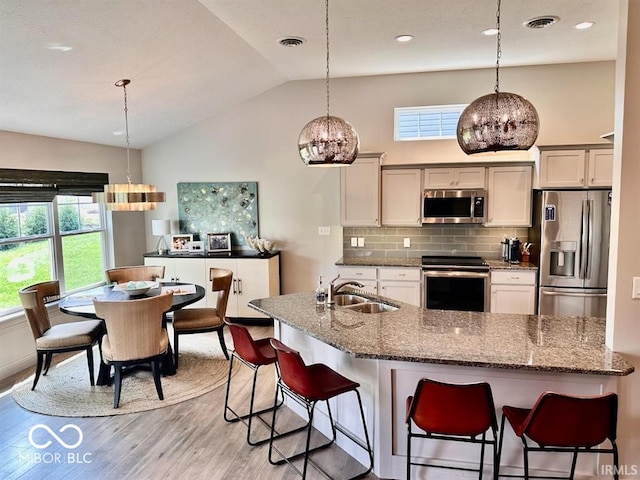 kitchen featuring an inviting chandelier, appliances with stainless steel finishes, sink, vaulted ceiling, and decorative light fixtures