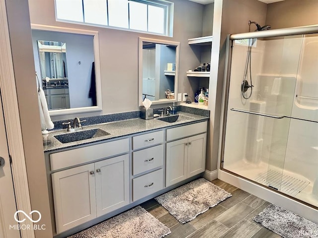 bathroom featuring double sink vanity and a shower with door