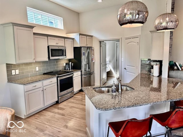 kitchen with a kitchen breakfast bar, stainless steel appliances, light hardwood / wood-style flooring, decorative backsplash, and kitchen peninsula