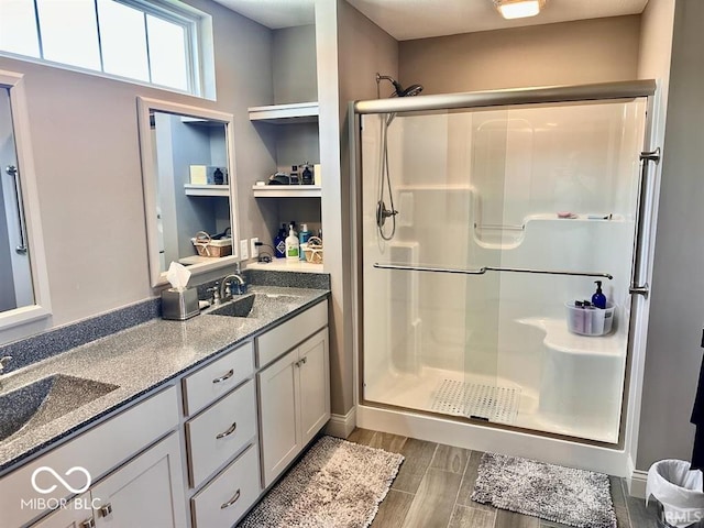 bathroom with wood-type flooring, double sink vanity, and a shower with door