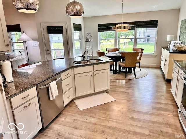 kitchen with dark stone countertops, white cabinets, stainless steel dishwasher, and light hardwood / wood-style floors