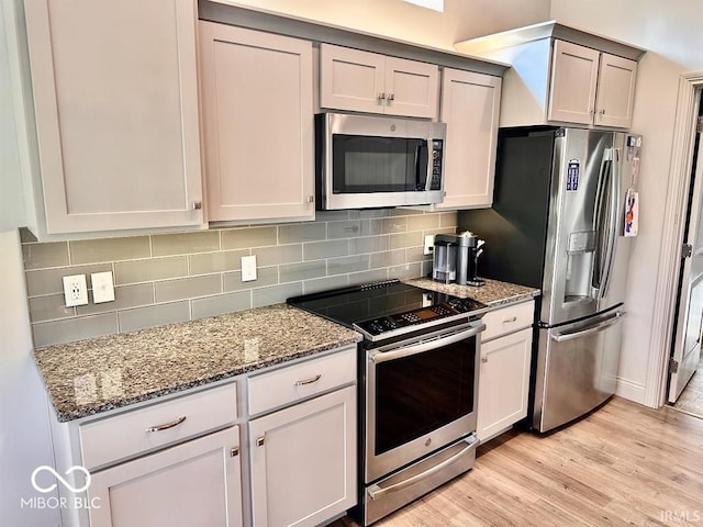 kitchen with appliances with stainless steel finishes, gray cabinets, decorative backsplash, and light hardwood / wood-style floors