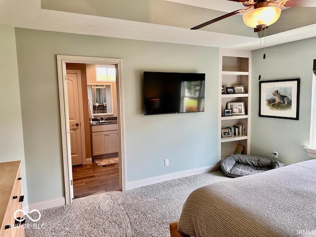 bedroom with ensuite bathroom, ceiling fan, sink, and carpet flooring