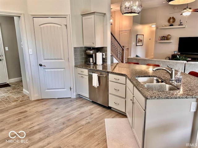 kitchen with ceiling fan, dishwasher, dark stone countertops, light wood-type flooring, and sink