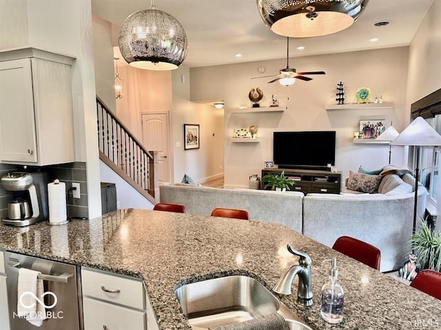 kitchen featuring white cabinetry, ceiling fan, dark stone counters, and sink