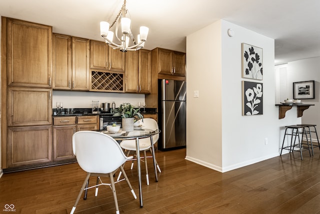 kitchen featuring stainless steel fridge, dark wood-type flooring, an inviting chandelier, and hanging light fixtures