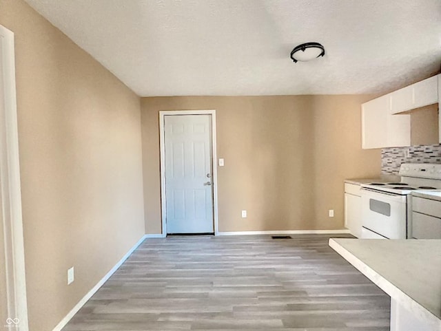 kitchen featuring decorative backsplash, white cabinetry, light hardwood / wood-style flooring, white range with electric cooktop, and a textured ceiling