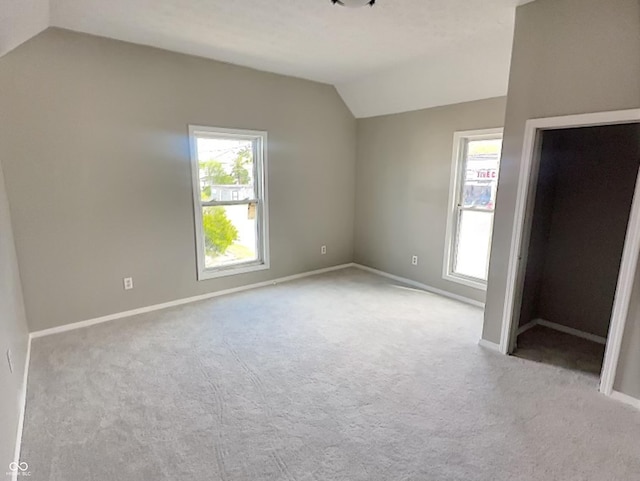 interior space with vaulted ceiling and light carpet