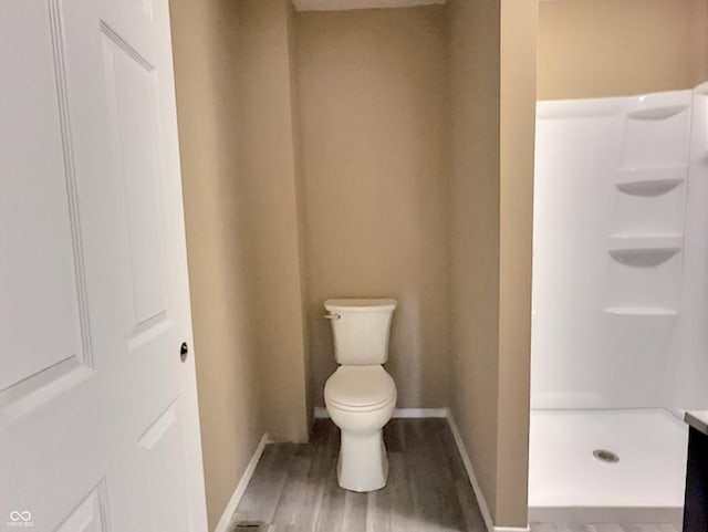 bathroom featuring toilet, a shower, and hardwood / wood-style floors