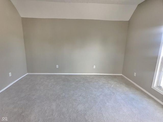 carpeted spare room featuring lofted ceiling