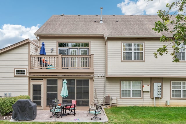 rear view of property with a patio, a lawn, and a balcony