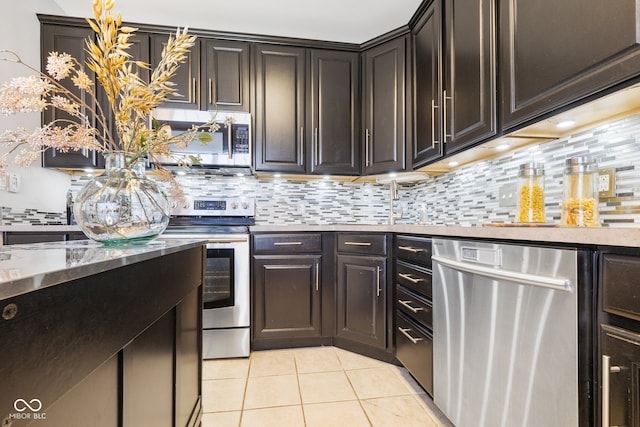 kitchen with dark brown cabinets, appliances with stainless steel finishes, light tile patterned flooring, and decorative backsplash