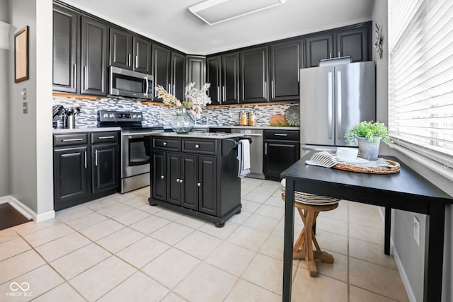 kitchen featuring stainless steel appliances, light tile patterned flooring, and backsplash