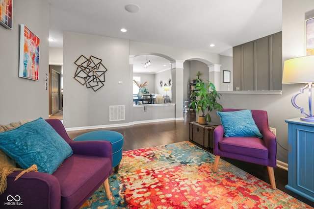 living area with wood-type flooring and decorative columns