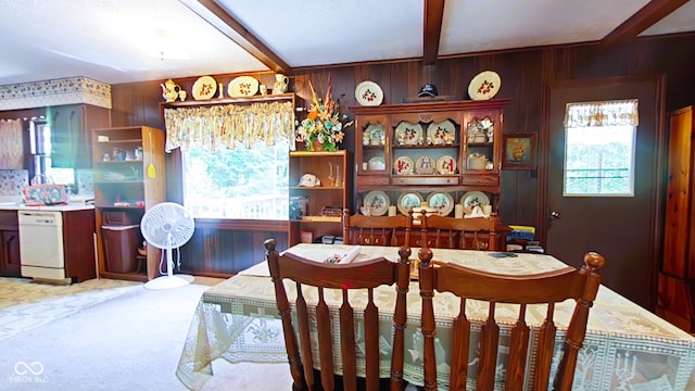 dining room with wood walls, carpet flooring, and beamed ceiling