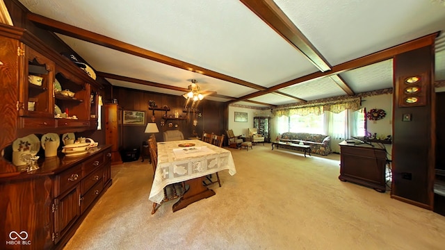 carpeted dining space with ceiling fan, wooden walls, and beam ceiling